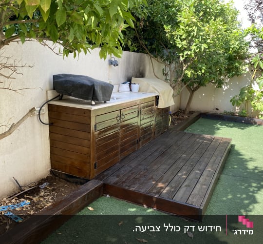 משטח עץ בגינה ליד ארון עץ עם כיסוי שחור